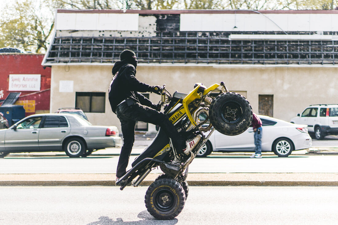 ATV wheelie in front of a corner store